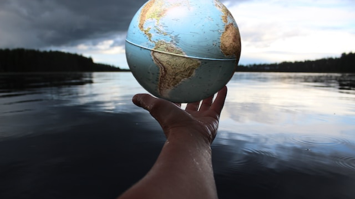 Person holding globe by a lake. Photo by Anne Nygård on Unsplash