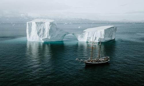 Schooner sailing by an iceberg in the Arctic. Photo by Annie Spratt on Unsplash