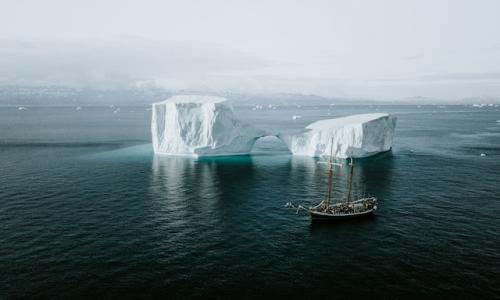 Schooner sailing by an iceberg in the Arctic. Photo by Annie Spratt on Unsplash