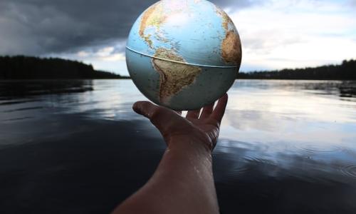 Person holding globe by a lake. Photo by Anne Nygård on Unsplash