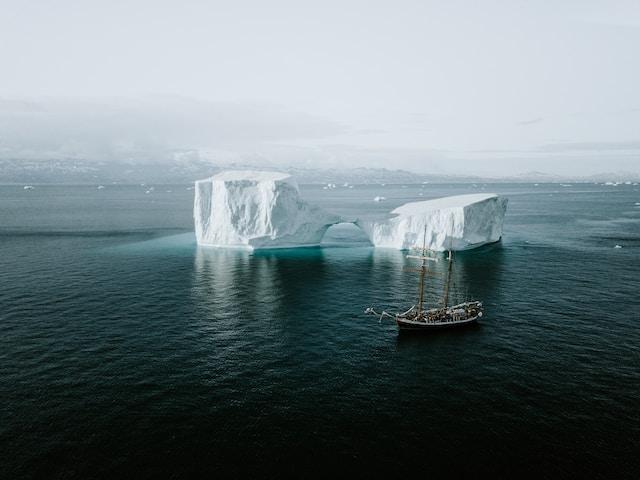 Schooner sailing by an iceberg in the Arctic. Photo by Annie Spratt on Unsplash